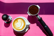 Top down photo of a Counter Culture Coffee tamper, a cappuccino, and a filled portafilter.
